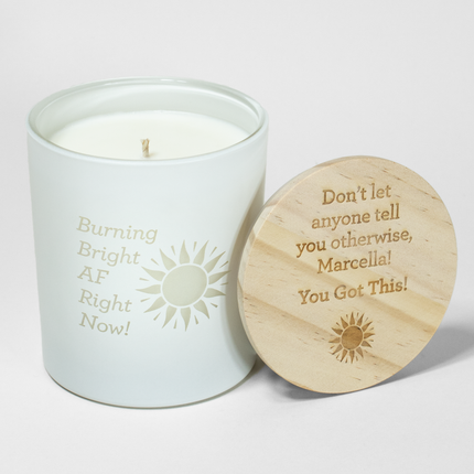 A white candle with a wooden lid, this 14 oz Custom Candles LA creation features "Burning Bright AF Right Now!" on the front. The lid offers empowering words: "Don't let anyone tell you otherwise, Marcella! You Got This!