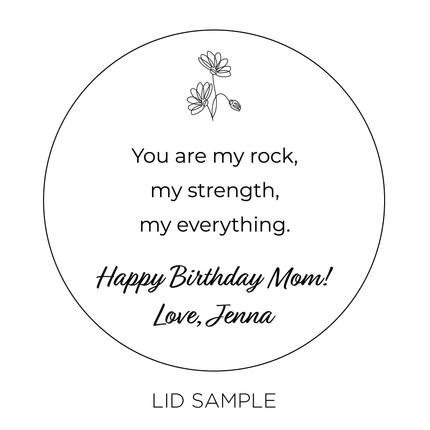 A sample of the wooden lid for the "I Love You Mom" Candle by Custom Candles L.A. features the message "You are my rock, my strength, my everything. Happy Birthday Mom! Love, Jenna" along with an illustration of small flower at the top of the lid.