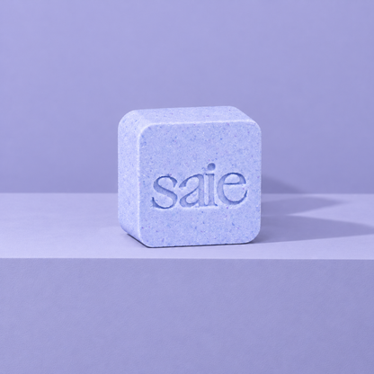 Lavender custom bath bomb with a debossed brand logo on a lavender backdrop, no foam