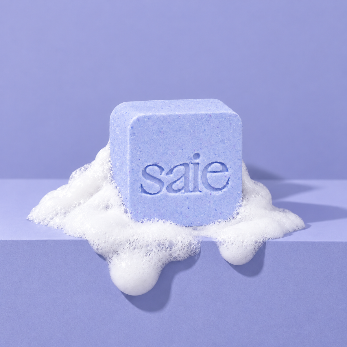 Lavender custom bath bomb with a debossed brand logo on a lavender backdrop, resting in white foam