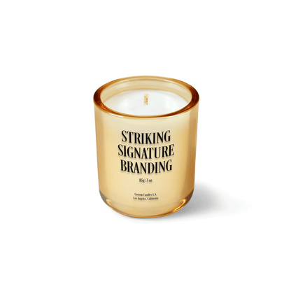 Glimmering gold 3 oz Mini Signature candle with a printed custom logo, shown on its own.