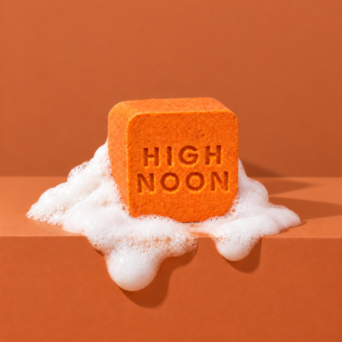 Orange custom bath bomb with a debossed brand logo on an orange backdrop, resting in white foam