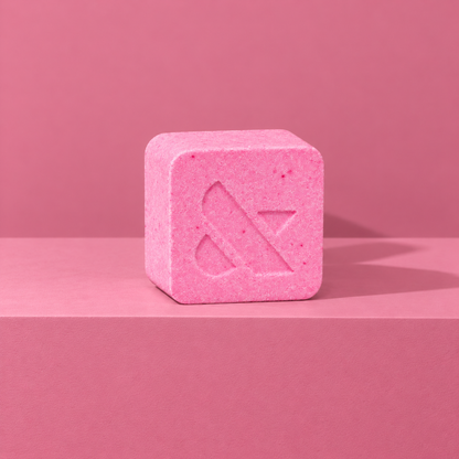 Pink custom bath bomb with a debossed brand logo on a pink backdrop, no foam