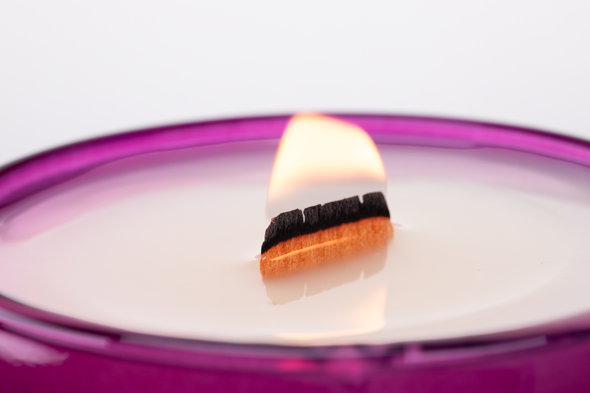 Purple 14 oz. Luxury Printed Candle burning, close-up of the flame and wax pool.