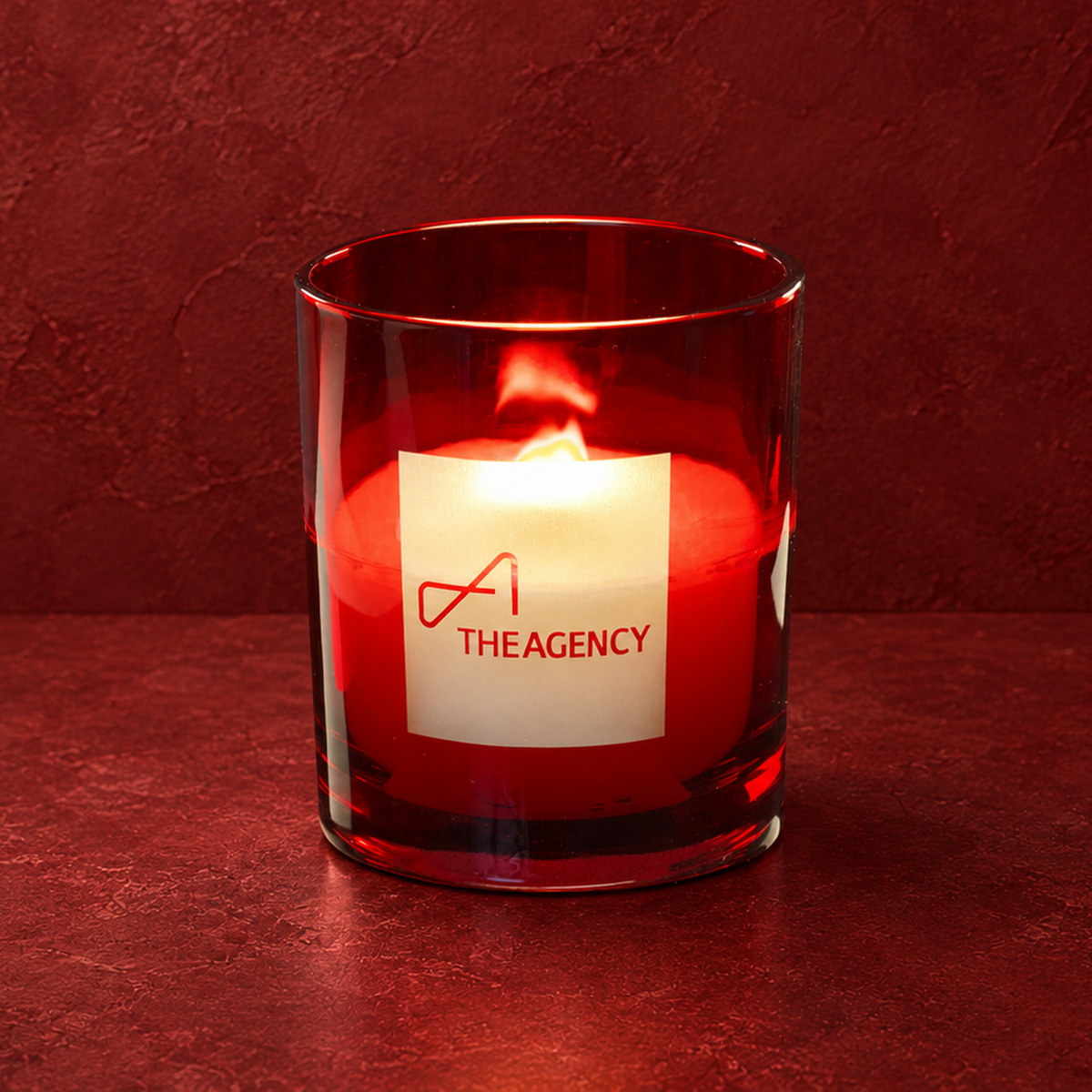 Red 14 oz. Luxury Engraved Candle with a custom engraved logo, lit.