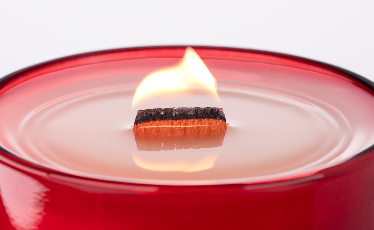 Red 14 oz. Luxury Engraved Candle burning, close-up of the flame and wax pool.