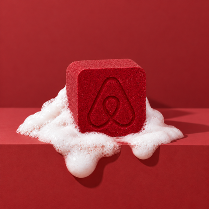 Red custom bath bomb with a debossed brand logo on a red backdrop, resting in white foam
