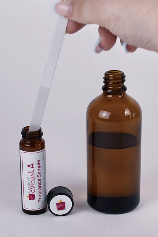 Hand holding a dropper over a large amber bottle with a small bottle labeled 'Couture LA' on a white background.