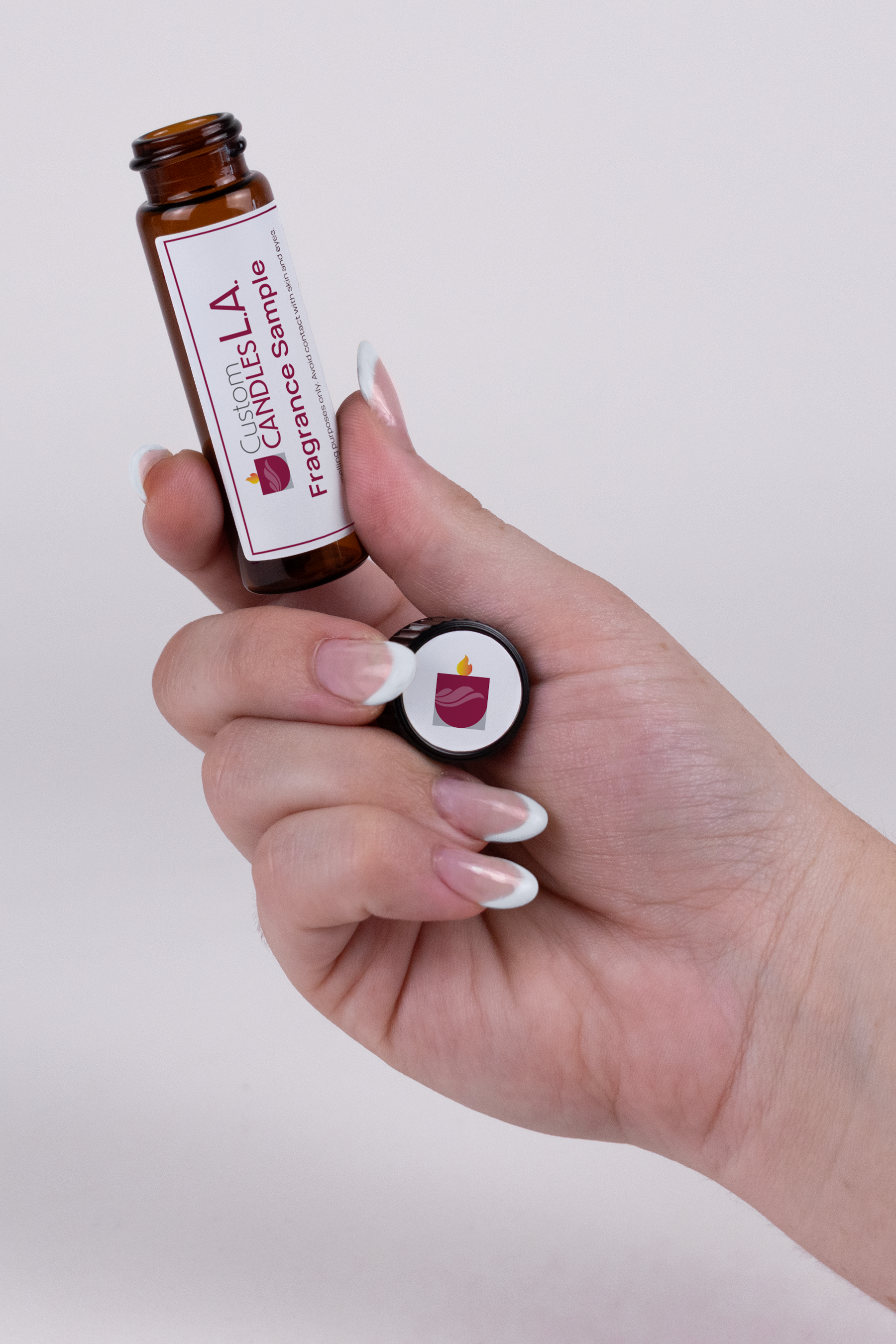 Hand holding a small brown bottle labeled 'Lavish LA' against a white background