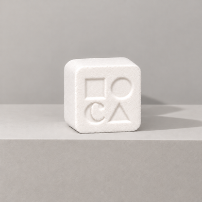 White custom bath bomb with a debossed brand logo on a gray backdrop, no foam