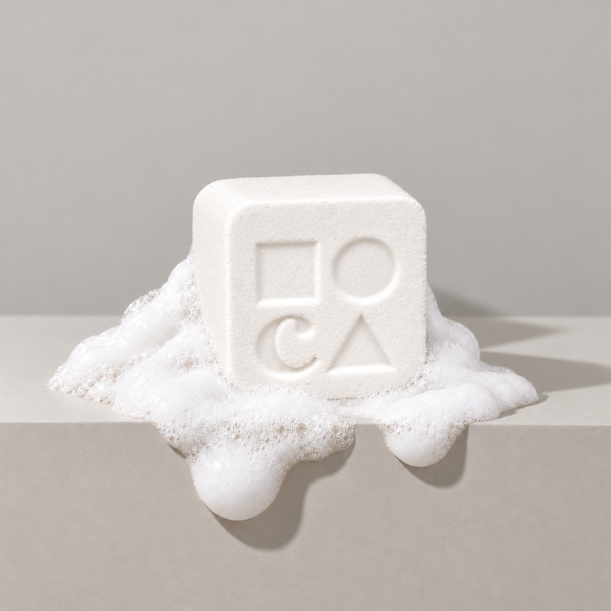 White custom bath bomb with a debossed brand logo on a gray backdrop, resting in white foam