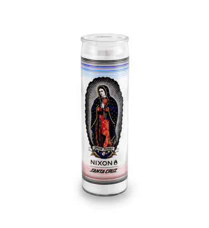 A 16 oz Prayer Candle from Custom Candles LA filled with white wax in a tall glass container. The candle is printed with a colorful image of a saint named "JASON JESSEE". Beneath the saint is a logo that reads "NIXON SANTA CRUZ" printed in black. Behind the saint imagery are horizontal lines surrounding the candle in black, blues, and reds. The white wax shows through the glass.