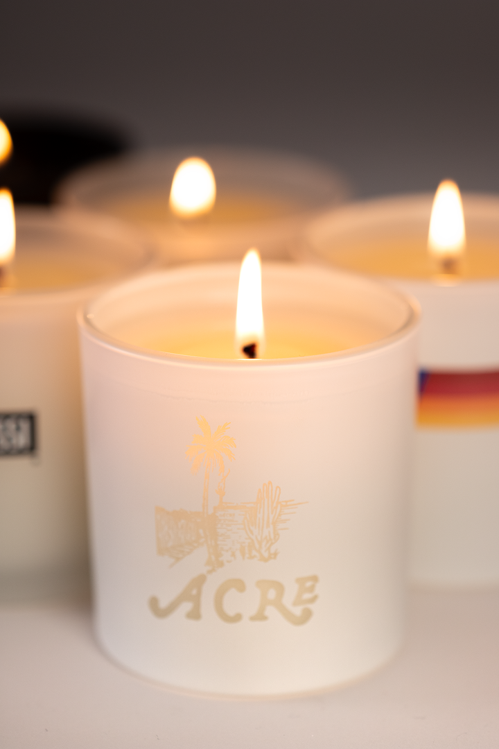 Frosted white 9 oz candle with a custom logo engraved into the glass, lit