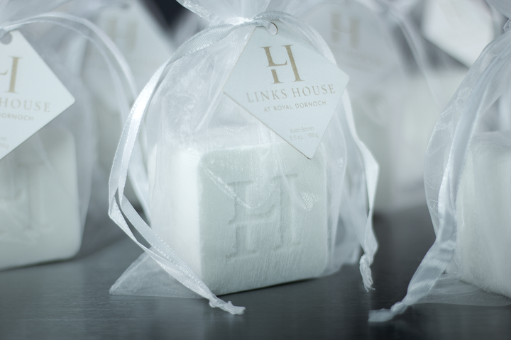 Custom bath bombs with a debossed hotel logo in white organza bags, close-up