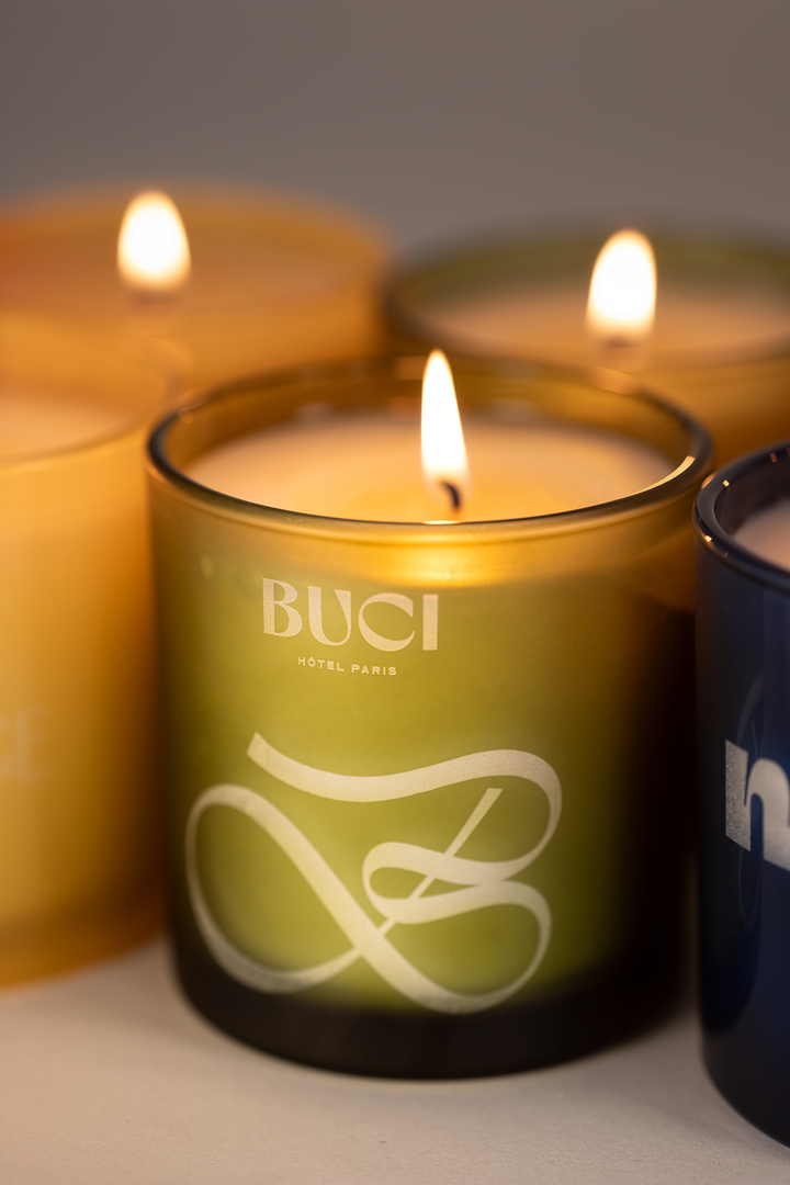Green glass 9 oz candle with a custom script logo engraved into the glass, lit
