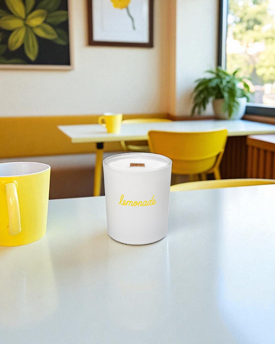 White candle with a bright yellow cursive script logo printed on it, sitting on a tabletop in a diner with matching yellow décor and seating