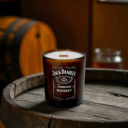 Amber candle with printed logo on a wooden barrel with a barrel and glass in the background.