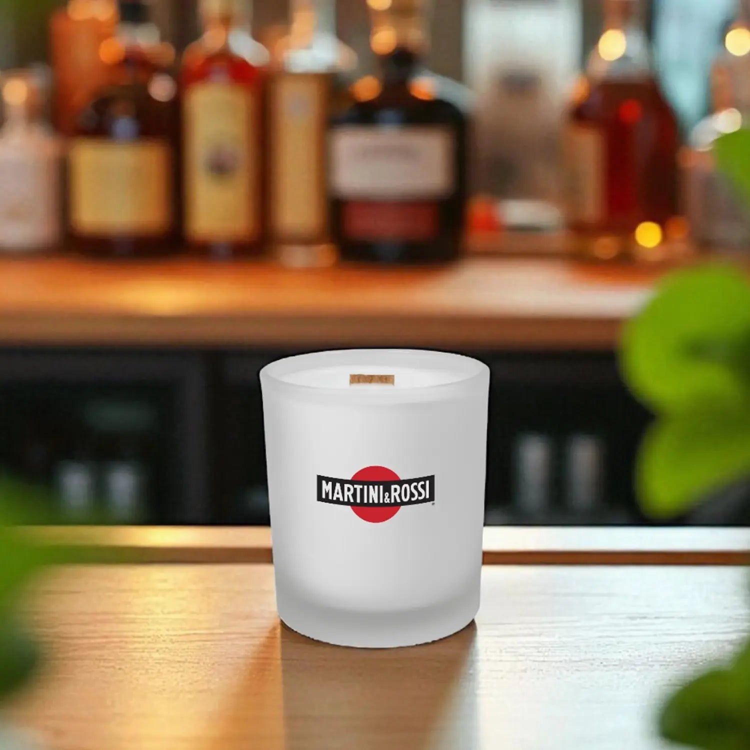 Frosted candle with printed logo on a bar counter with blurred bottles in the background