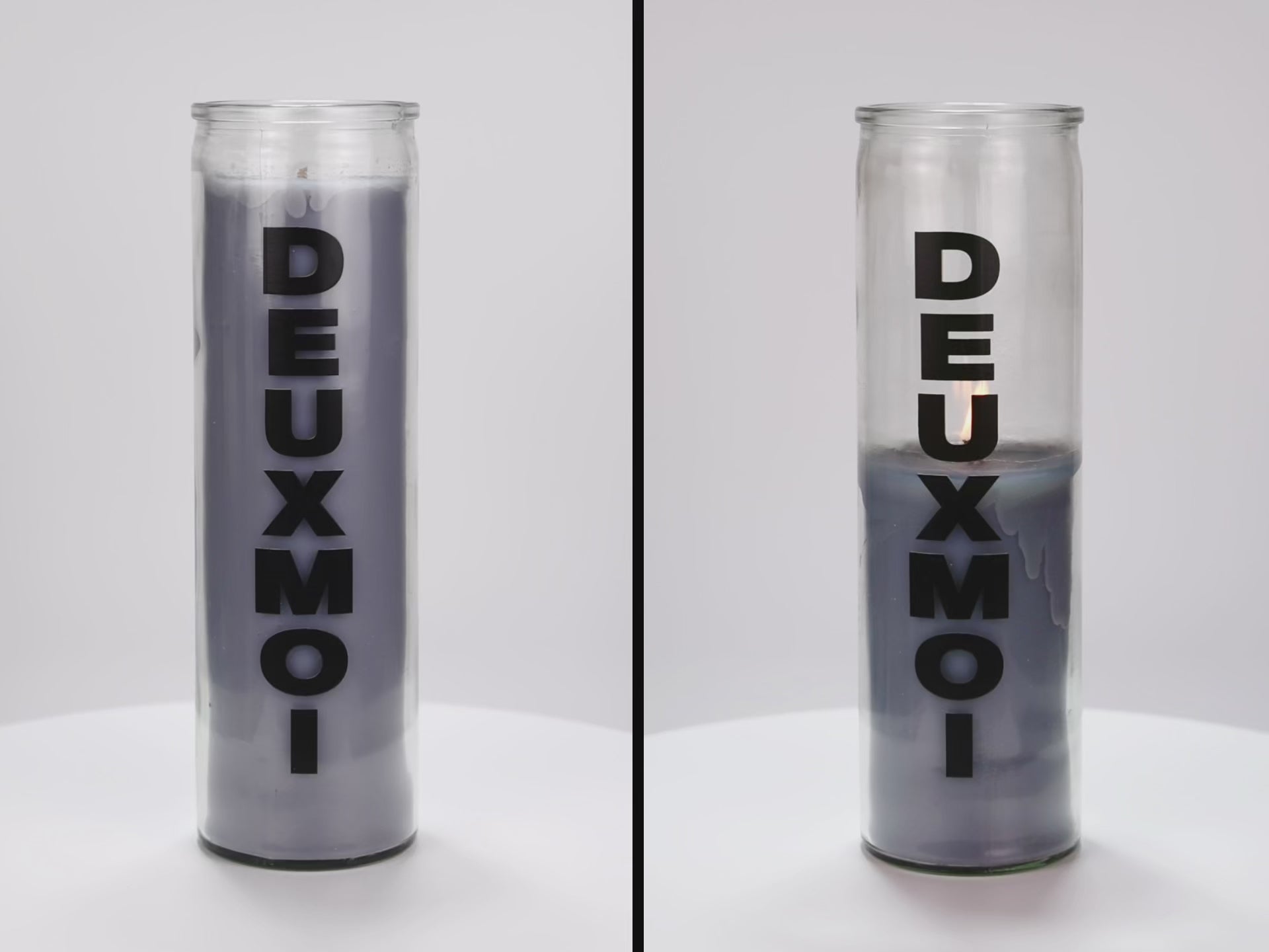 Load video: Two 16 oz Prayer Candles from Custom Candles LA filled with gray wax in a tall glass container spinning side by side. The candles are printed with a logo that reads &quot;DEUXMOI&quot; in bold black letters that are stacked vertically down the front of the glass.