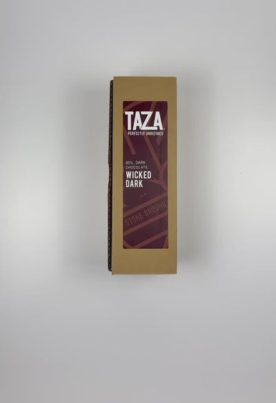 An unboxing video of the 16 oz Prayer Candle from Custom Candles LA filled with brown wax that comes in a Kraft mailer box with a brown sticker label of the logo artwork. The candle is printed with a logo that reads "TAZA Perfectly Unrefined" in white and "95% Dark Chocolate Wicked Dark" printed underneath it, with a brown circle that includes lines printed in brown along with "Stone Ground" behind the logo. The brown wax shows through the image.