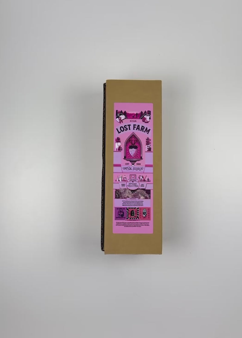 An unboxing video of the 16 oz Prayer Candle from Custom Candles LA filled with pink wax that comes in a Kraft mailer box with a pink sticker label of the logo artwork. The candle is printed with a logo that reads "KIVA LOST FARM PINK JESUS" in black. Printed in various pinks and black is imagery of a strawberry in a church like window surrounded by the logo and a silhouette of a farm. The pink wax shows through the imagery. 