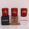 Three lit 12 oz Luxe Custom Candles in the color “Blood Red” which is a vivid rouge from Custom Candles LA. The 1st candle has the "Gooseberry" logo printed on the glass in white and sits on a black box that has the same logo printed on it. The 2nd candle has a pink "Medly Wine Co." logo printed on the glass and sits on top of a Kraft box with the logo printed in red. The 3rd candle has a "P" etched on the glass, and sits on a white box with the logo "Petersen Automotive Museum" printed in red.