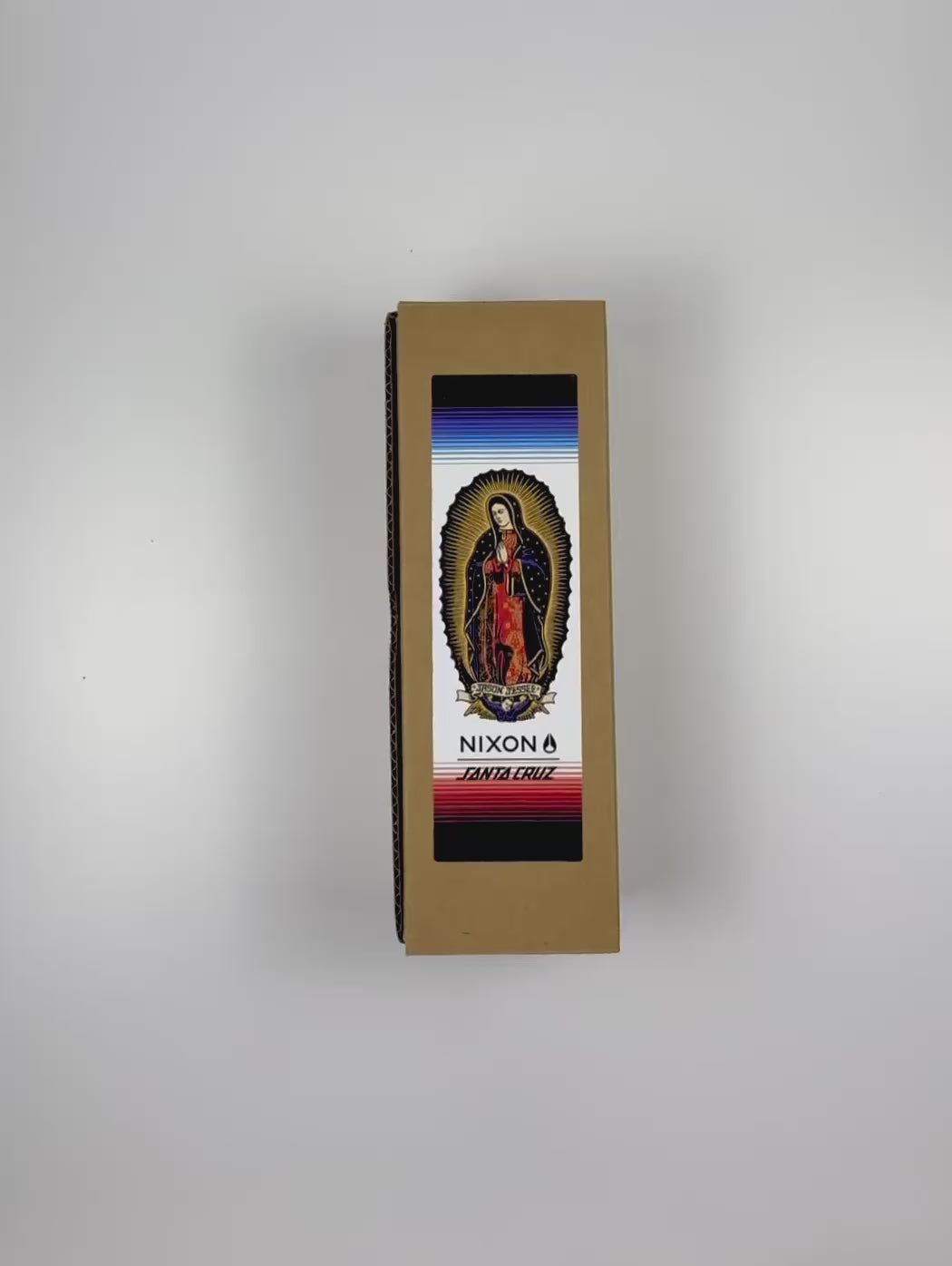 An unboxing video of the 16 oz Prayer Candle from Custom Candles LA filled with white wax that comes in a Kraft mailer box with a colorful sticker label of a saint. The candle is printed with a colorful image of a saint named "JASON JESSEE". Beneath the saint is a logo that reads "NIXON SANTA CRUZ" printed in black. Behind the saint imagery are horizontal lines surrounding the candle in black, blues, and reds. The white wax shows through the glass.