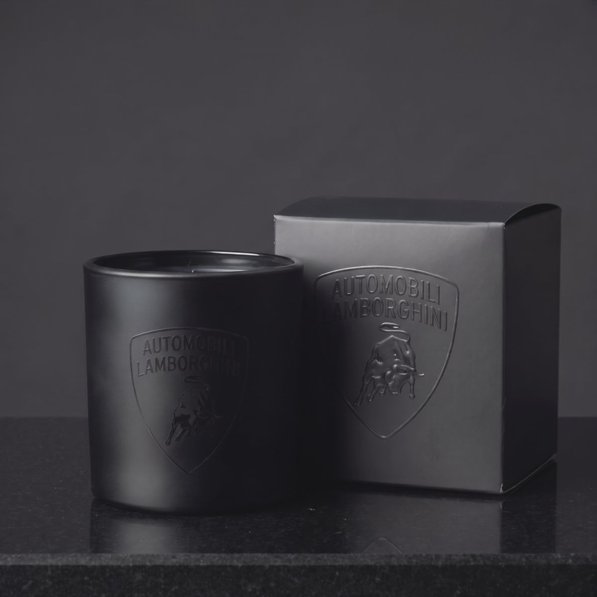 Video of a custom printed 9 oz matte black candle with a gloss black logo catching the light beside its branded gift box, made in Los Angeles by Custom Candles LA