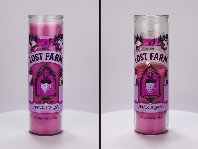 Two 16 oz Prayer Candles from Custom Candles LA filled with pink wax in a tall glass container spinning side by side. The candles are printed with a logo that reads "KIVA LOST FARM PINK JESUS" in black. Printed in various pinks and black is imagery of a strawberry in a church like window surrounded by the logo and a silhouette of a farm. The pink wax shows through the imagery. 