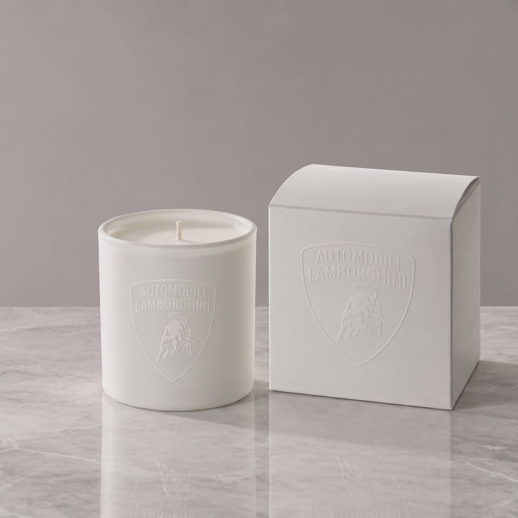 Matte white 9 oz. Classic Candle lit, with a tone-on-tone Lamborghini shield logo glowing beside its white gift box, made in Los Angeles by Custom Candles LA
