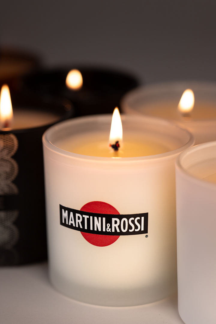 Frosted white 9 oz candle printed with a full-color spirits brand logo, lit